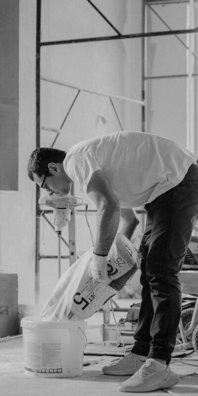A construction worker pours materials inside a building under renovation.