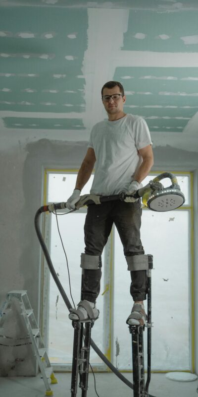A construction worker using stilts for ceiling renovation indoors, enhancing space with expertise.