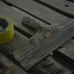 Close-up of a spatula and duct tape on an aged wooden surface. Perfect for DIY and renovation themes.