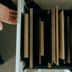 Top view of assorted wooden panels neatly arranged in a drawer with a hand reaching out.
