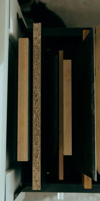 Top view of assorted wooden panels neatly arranged in a drawer with a hand reaching out.